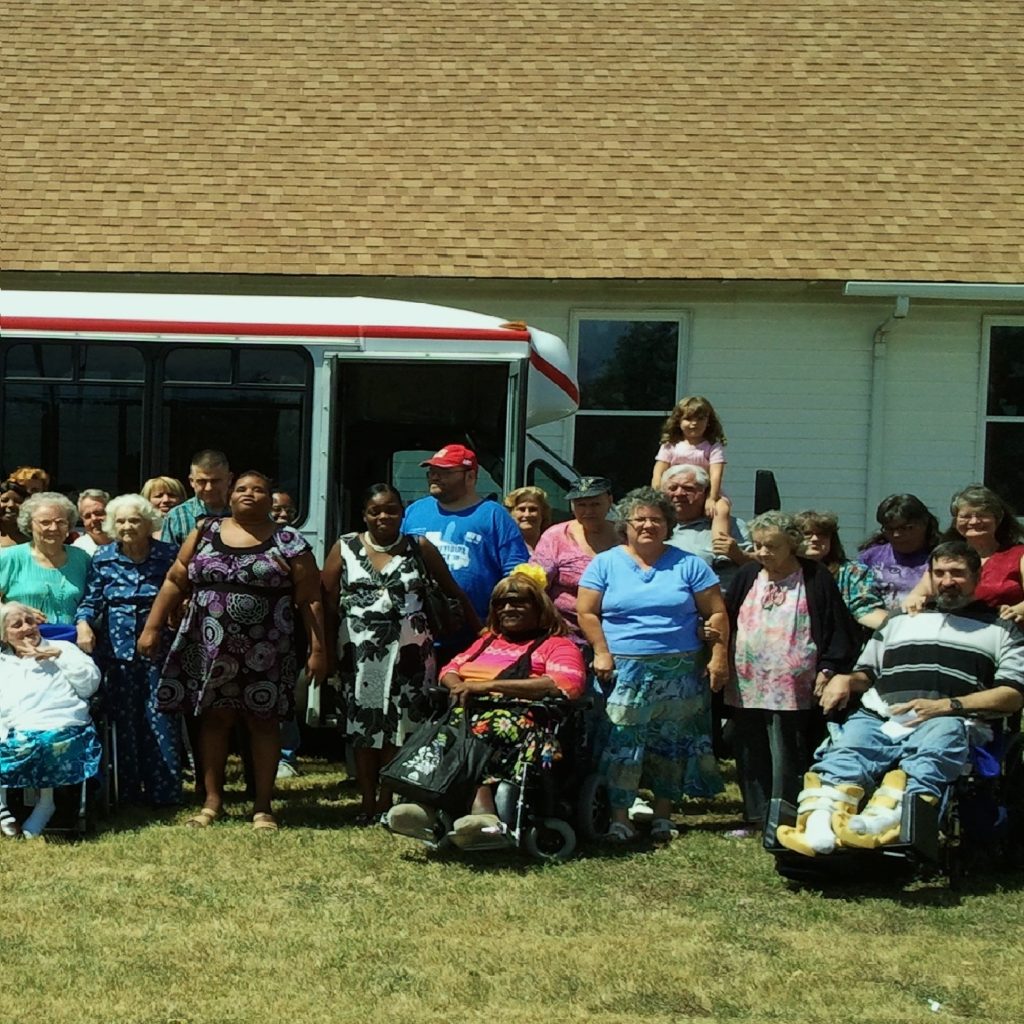 Church members on the lawn with lift-equipped van and building in background